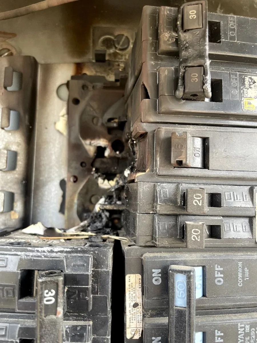 Charred circuit breakers on a panel bus bar